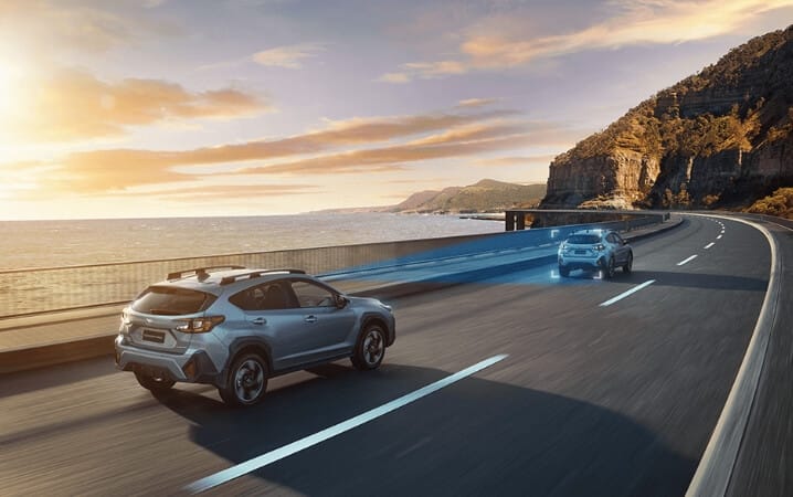 SUVs driving along coastal highway at sunset