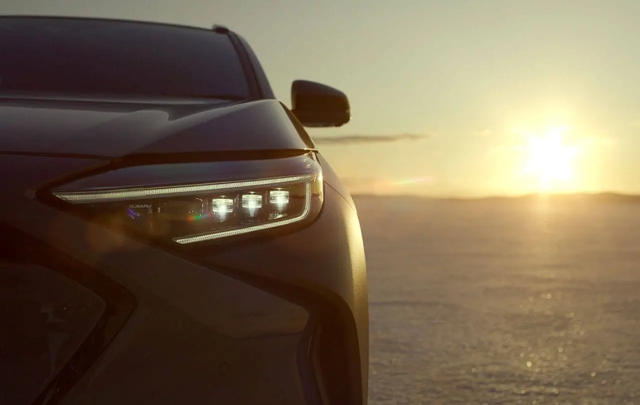 Subaru Solterra headlights gleaming at sunset on salt flats - Subaru Crosstrek