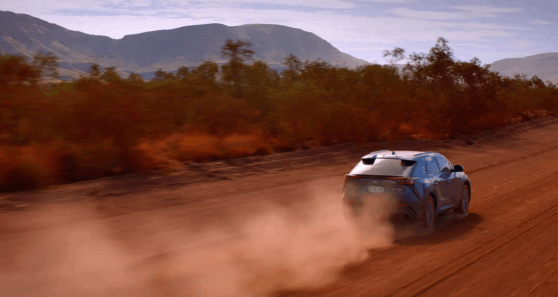 Rear view of a Subaru Solterra on an unsealed road, dust cloud rising behind it