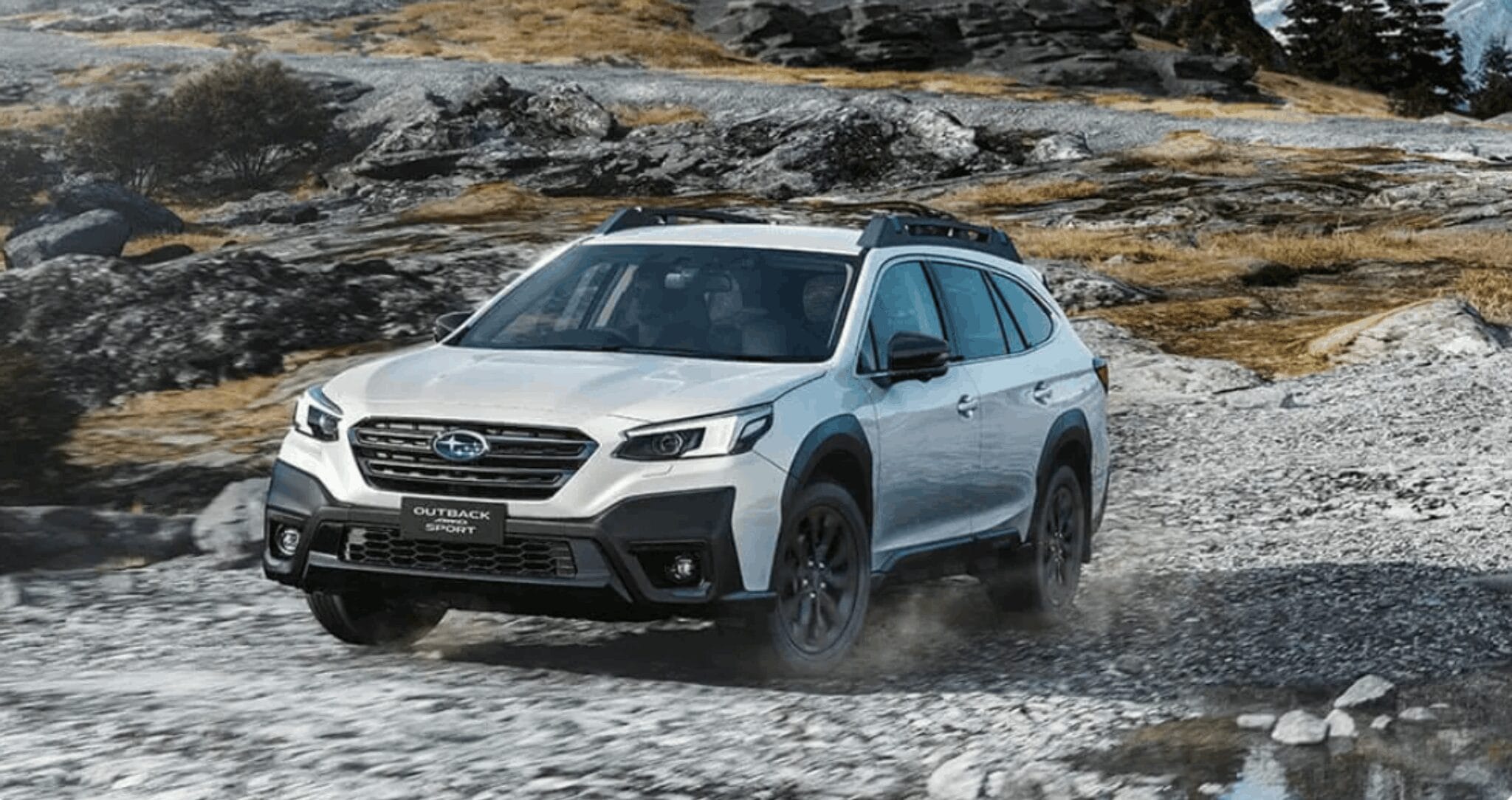 Subaru Outback driving over rocky terrain in a rugged off-road landscape