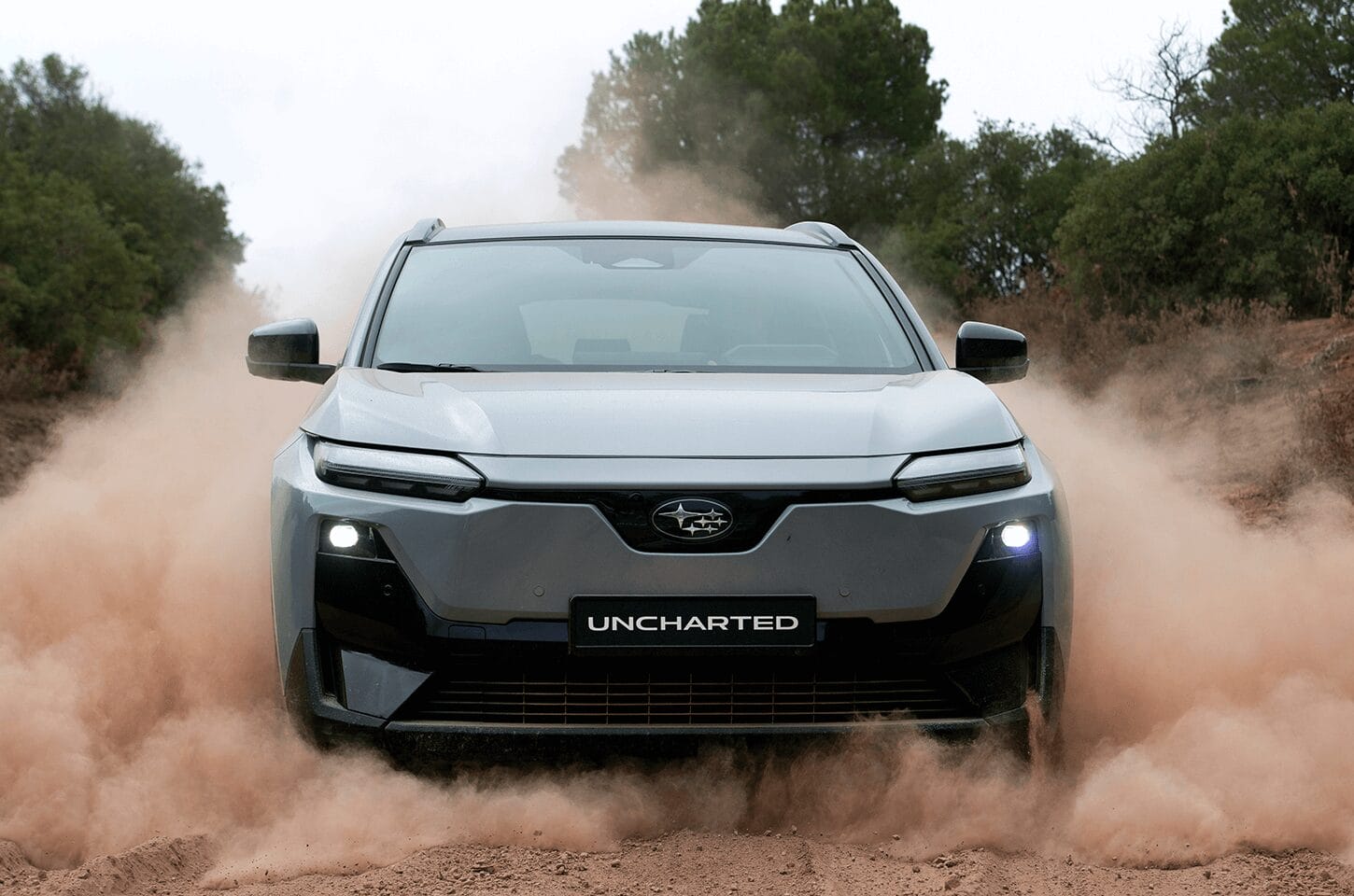 Grey Subaru Uncharted driving through dust on an off-road trail showcasing AWD capability.