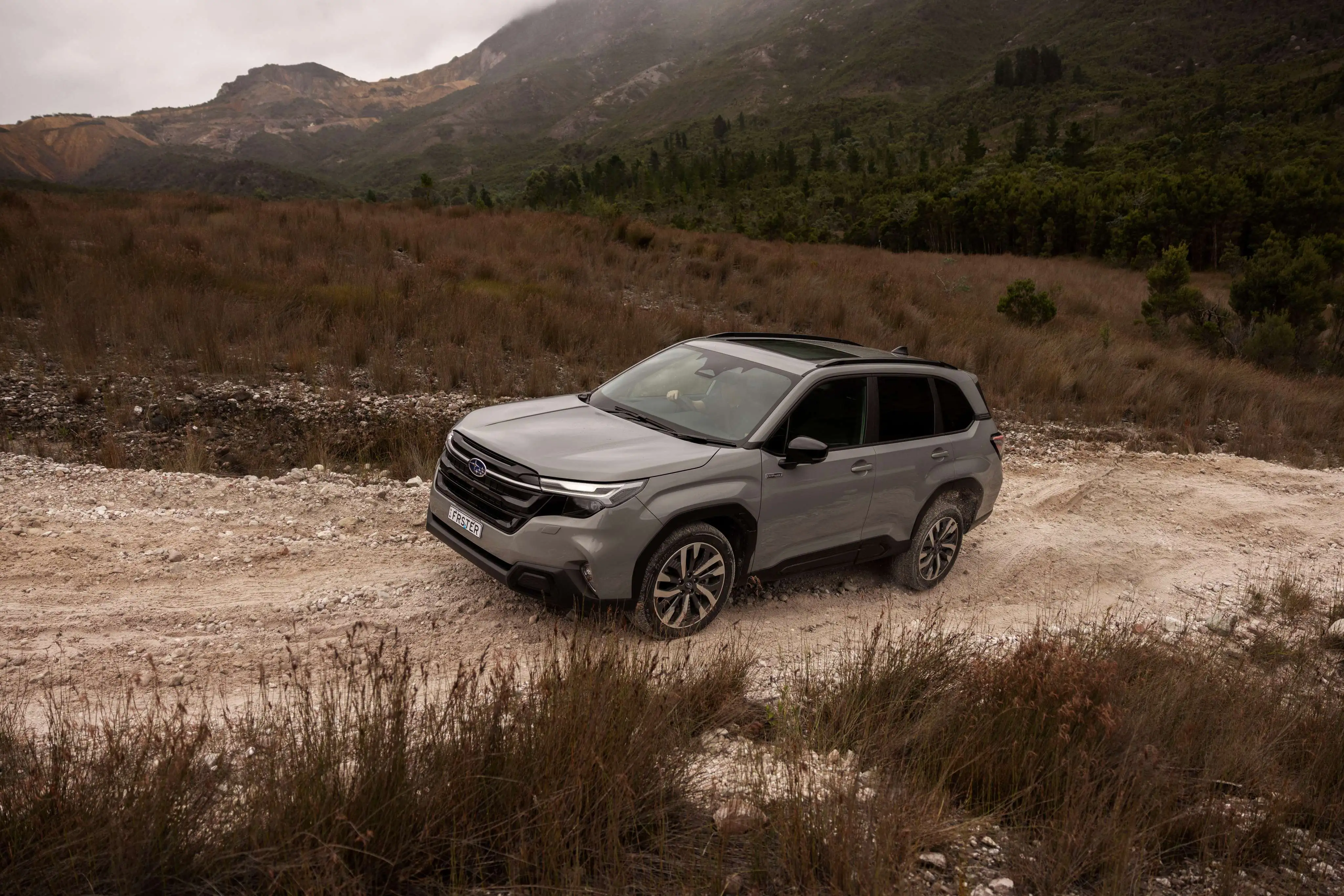 MY26 Forester AWD Hybrid Touring Driving up dirt road Hill