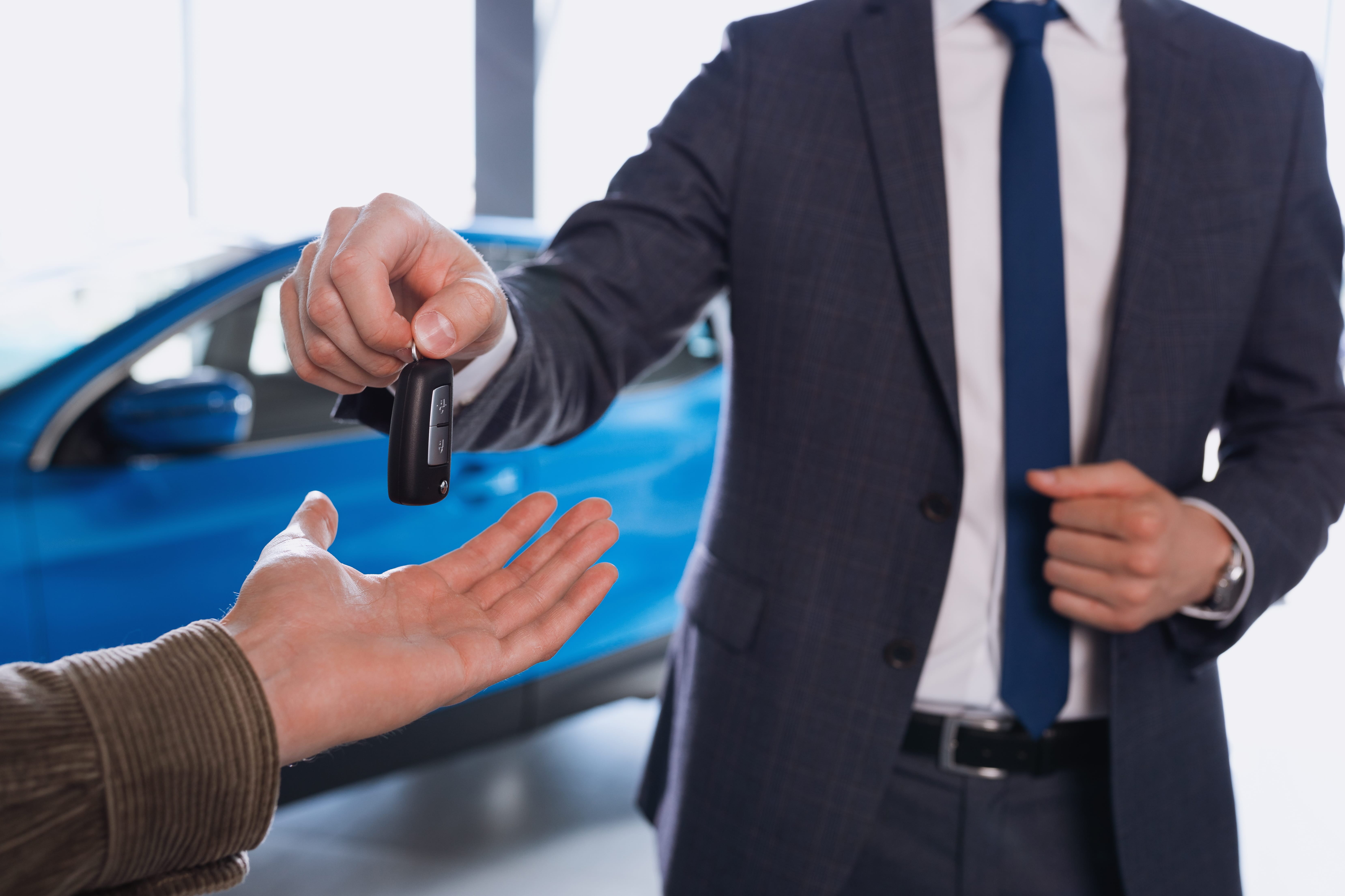Sales manager handing over car keys to a customer, representing the moment a private car sale differs from a dealer trade-in
